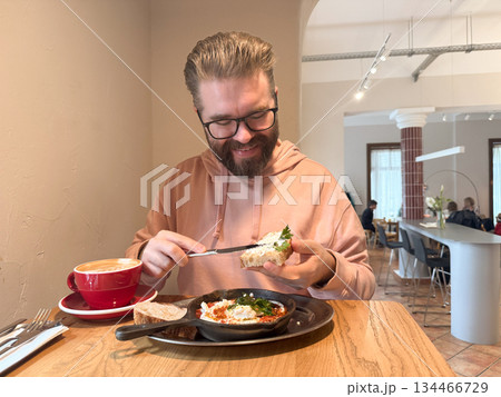 Man dining alone in cafe with breakfast. Morning calm, slow living and appreciation of simple comfort through food and space. Man dining alone in cafe with breakfast. Morning calm, slow living and appreciation of simple comfort through food and space. 134466729