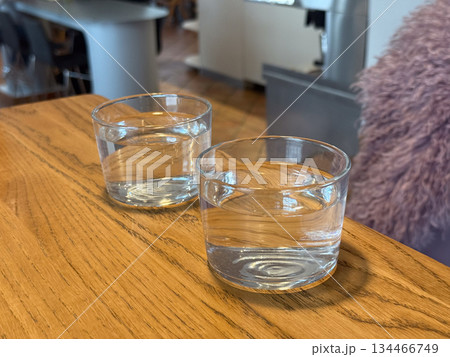 Two glasses of water on wooden cafe table. Simplicity, hydration, and calm atmosphere in social dining environment. 134466749
