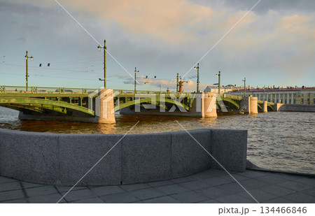 view of the Birzhevoy bridge and Institute of Russian Literature at sunset, lampposts on the bridge, Neva River with a view of the arrow of Vasilyevsky Island with rostral columns view of the Birzhevoy bridge and Institute of Russian Literature at sunset, lampposts on the bridge, Neva River with a view of the arrow of Vasilyevsky Island with rostral columns 134466846