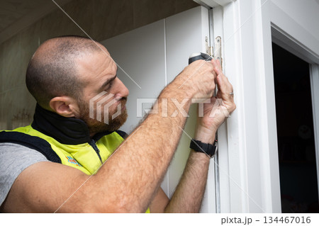 Young man fixing a door with a screwdriver 134467016