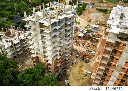 Aerial view of tower lifting crane and concrete frame of tall apartment residential buildings under construction in a city. Urban development and real estate growth concept. 134467194