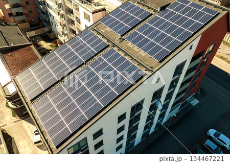Aerial view of solar photovoltaic panels on a roof top of residential building block for producing clean electric energy. Autonomous housing concept. Aerial view of solar photovoltaic panels on a roof top of residential building block for producing clean electric energy. Autonomous housing concept. 134467221