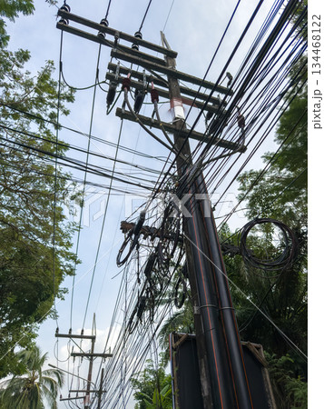 Asian poles with lots of wires at sunset, telecommunications in Thailand, chaos in the wires Asian poles with lots of wires at sunset, telecommunications in Thailand, chaos in the wires 134468122
