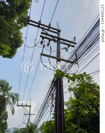 Asian poles with lots of wires at sunset, telecommunications in Thailand, chaos in the wires Asian poles with lots of wires at sunset, telecommunications in Thailand, chaos in the wires 134468123