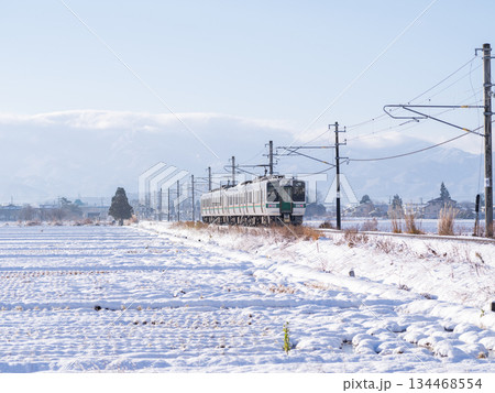 【山形線】冬の田園風景を走行する普通列車 134468554