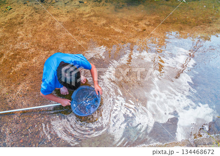 楽しい夏休みに日差しを浴びて川遊びをしている少年 134468672