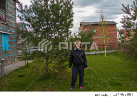 Portrait of happy elderly beautiful woman near beautiful fir trees in her garden. 134468987
