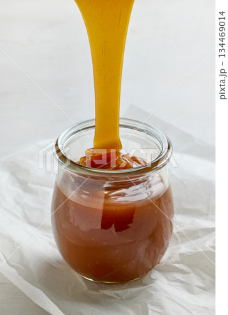 freshly cooked homemade caramel sauce pouring in jar 134469014