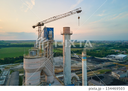 Aerial view of cement factory with high concrete plant structure and tower crane at industrial production site. Manufacture and global industry concept Aerial view of cement factory with high concrete plant structure and tower crane at industrial production site. Manufacture and global industry concept 134469503