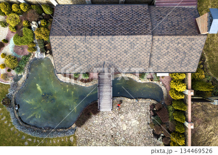Aerial view of beautifully landscaped recreation house cottage complex with pond in ecological area on bright sunny day. Modern architecture, riches and luxury concept. 134469526