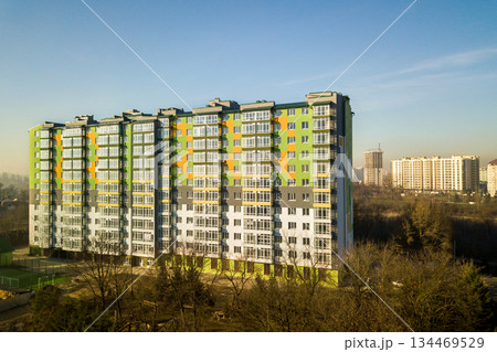 Aerial view of a tall residential apartment building with many windows and balconies. Aerial view of a tall residential apartment building with many windows and balconies. 134469529