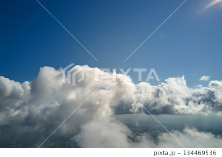 Aerial view from airplane window at high altitude of earth covered with puffy cumulus clouds forming before rainstorm Aerial view from airplane window at high altitude of earth covered with puffy cumulus clouds forming before rainstorm 134469536