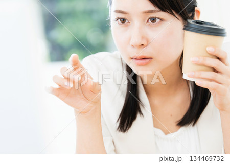 仕事をしながらコーヒーを飲む女性 仕事をしながらコーヒーを飲む女性 134469732