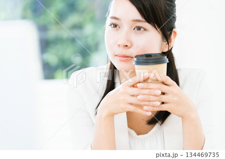 仕事をしながらコーヒーを飲む女性 仕事をしながらコーヒーを飲む女性 134469735