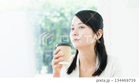 仕事をしながらコーヒーを飲む女性 仕事をしながらコーヒーを飲む女性 134469739