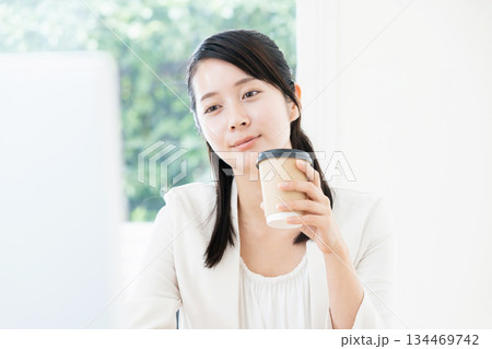 仕事をしながらコーヒーを飲む女性 134469742
