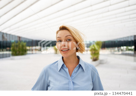 Confident businesswoman smiling near modern office Confident businesswoman smiling near modern office 134470441