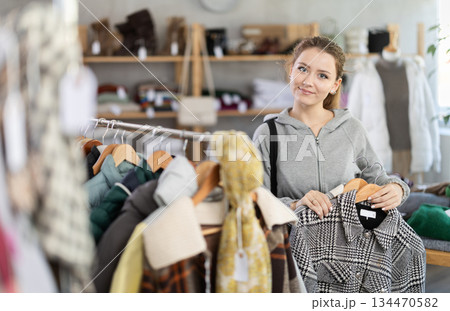 Young woman near showcase examine goods, buying autumn jacket. Young woman near showcase examine goods, buying autumn jacket. 134470582