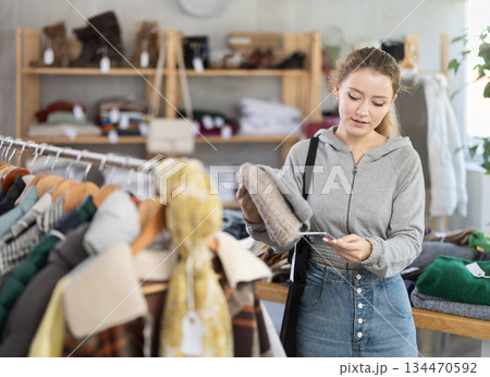 Young woman near showcase examine goods, hat. 134470592