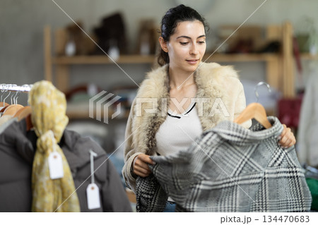 Young woman chooses jacket in clothing store 134470683