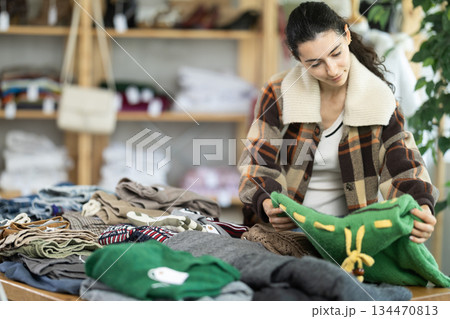 Armenian woman stands near the counter and chooses jersey sweaters 134470813