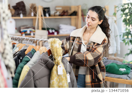 Young woman chooses outerwear in store Young woman chooses outerwear in store 134471056