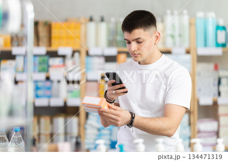 Young man in pharmacy scans QR code on tablets box 134471319