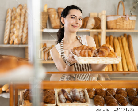 Young woman seller with basket of croissants Young woman seller with basket of croissants 134471375