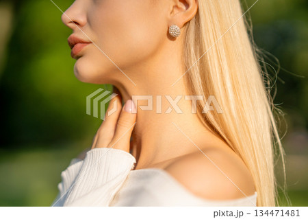 Model lightly touches her neck, bathed in sunlight Model lightly touches her neck, bathed in sunlight 134471481