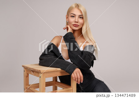 Model poses gracefully on a stool, lost in thought 134471489