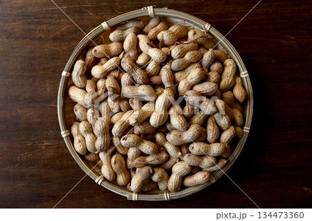 真上から見たテーブル背景の竹ざるに盛った沢山の殻付き落花生 134473360