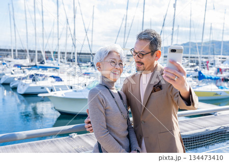港で自撮りをするシニア夫婦　撮影協力:道の駅伊東マリンタウン 134473410