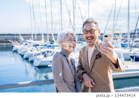 港で自撮りをするシニア夫婦　撮影協力:道の駅伊東マリンタウン 134473414