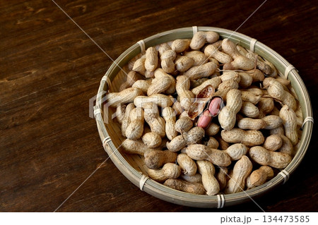 テーブル背景の竹ざるに盛った沢山の殻付き落花生 テーブル背景の竹ざるに盛った沢山の殻付き落花生 134473585