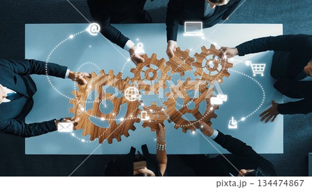 Collaborative Business Strategy with Wooden Gears Illustrating Teamwork, Innovation, and Networking Above a Table in a Modern Office Setting. Raster 134474867