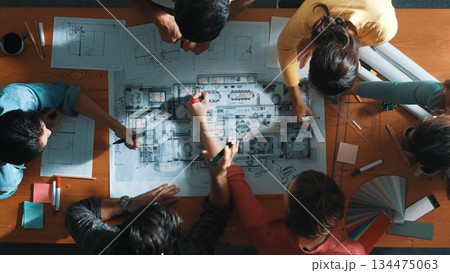 Top down view of engineer team writing at blueprint at meeting table. Symposium. Top down view of engineer team writing at blueprint at meeting table. Symposium. 134475063