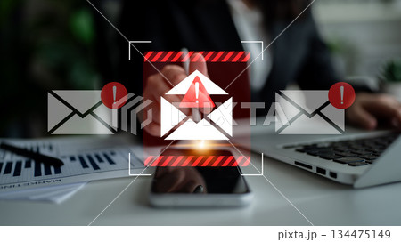 Business professional analyzing emails with warning notifications against a modern office backdrop to emphasize digital communication risks and alerts Gantry Business professional analyzing emails with warning notifications against a modern office backdrop to emphasize digital communication risks and alerts Gantry 134475149