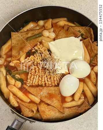 Spicy Korean tteokbokki with chewy rice cakes in a vibrant red sauce, topped with sesame seeds and green onions. A popular street food known for its addictive flavor and satisfying texture. 134475552