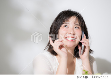 嬉しい楽しいスマホをで話す若い女性クローズアップ　問合せやコンタクトの表情 134475687