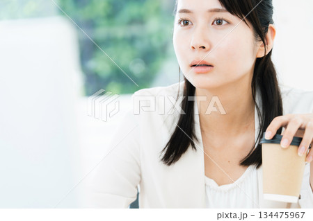 仕事をしながらコーヒーを飲む女性 仕事をしながらコーヒーを飲む女性 134475967
