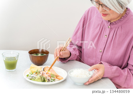 自宅のダイニングで食事をするグレイヘアのシニア女性 自宅のダイニングで食事をするグレイヘアのシニア女性 134480059