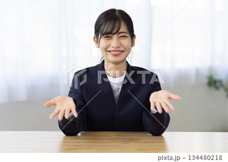 デスクで笑顔で胸の前に手を出す若いビジネスウーマン 134480218