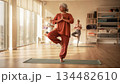 Portrait of an elderly lady practicing yoga in a gym, an adult native American woman stands on a mat, mindfulness and yoga practice for older adults 134482610