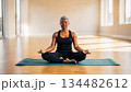 Meditation and exercise practice. An adult African American woman sits on a mat in a gym after exercise. Mindfulness and yoga practice for older adults 134482612