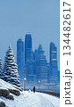 copy space New Year's poster depicting snowfall in a big city on Christmas Eve. A man and a snowman admire the snow from a park across from the city center. 134482617