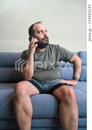 Man talks on phone while sitting at home Man talks on phone while sitting at home 134483243