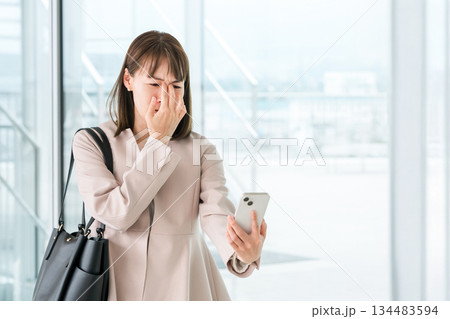 老眼,かすみ目,眼精疲労でスマホの画面がよく見えないアジア人ビジネスウーマン 134483594