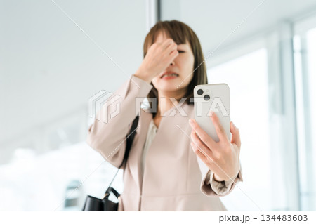 老眼,かすみ目,眼精疲労でスマホの画面がよく見えないアジア人ビジネスウーマン 老眼,かすみ目,眼精疲労でスマホの画面がよく見えないアジア人ビジネスウーマン 134483603