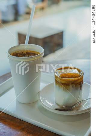 Ice Cream Latte and Paper Cup Iced Americano on a Cafe Tray by the Window 134484299