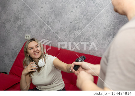 Woman on Red Sofa Receives Video Game Controller From a Man 134484914